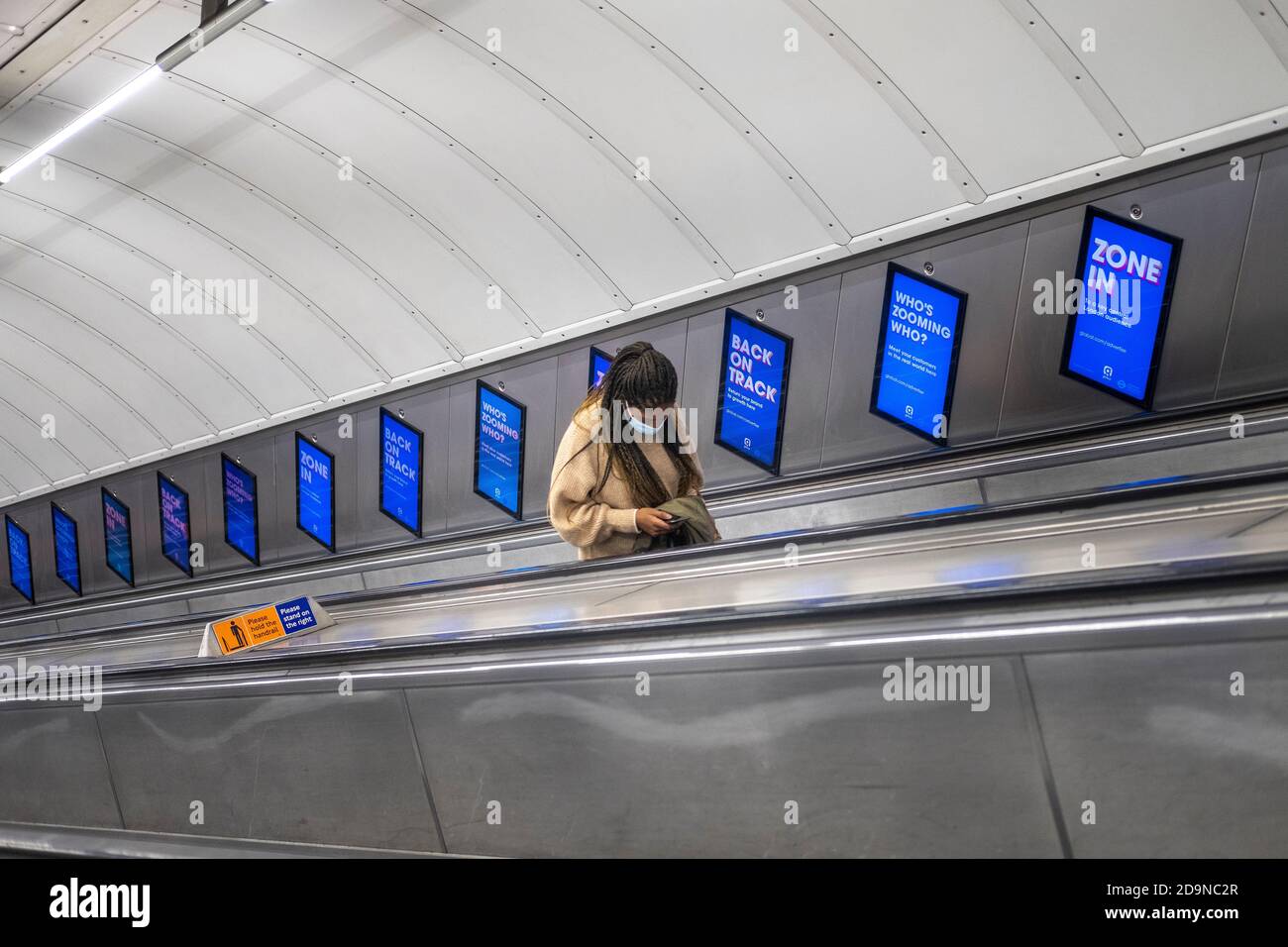 Commuter wearing face mask on escalator in London Underground, during