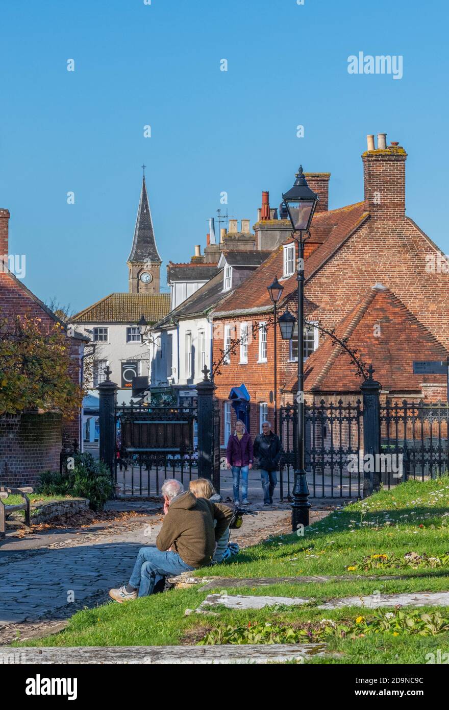a couple sitting relaxing on a wall in the grouns of christchurch priory in hampshire, uk Stock Photo