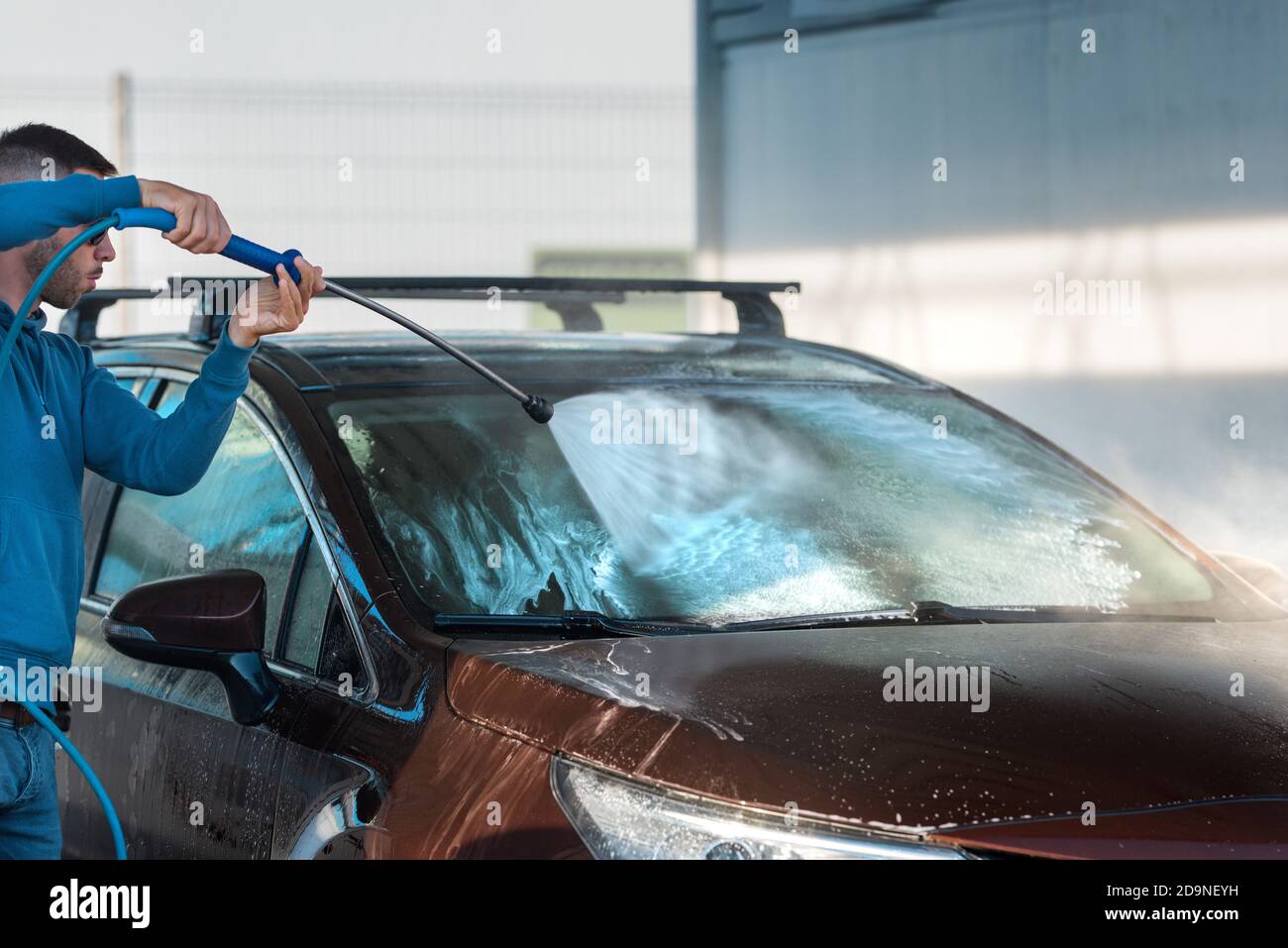 Self serve car washing. Man cleaning car using high pressure water at