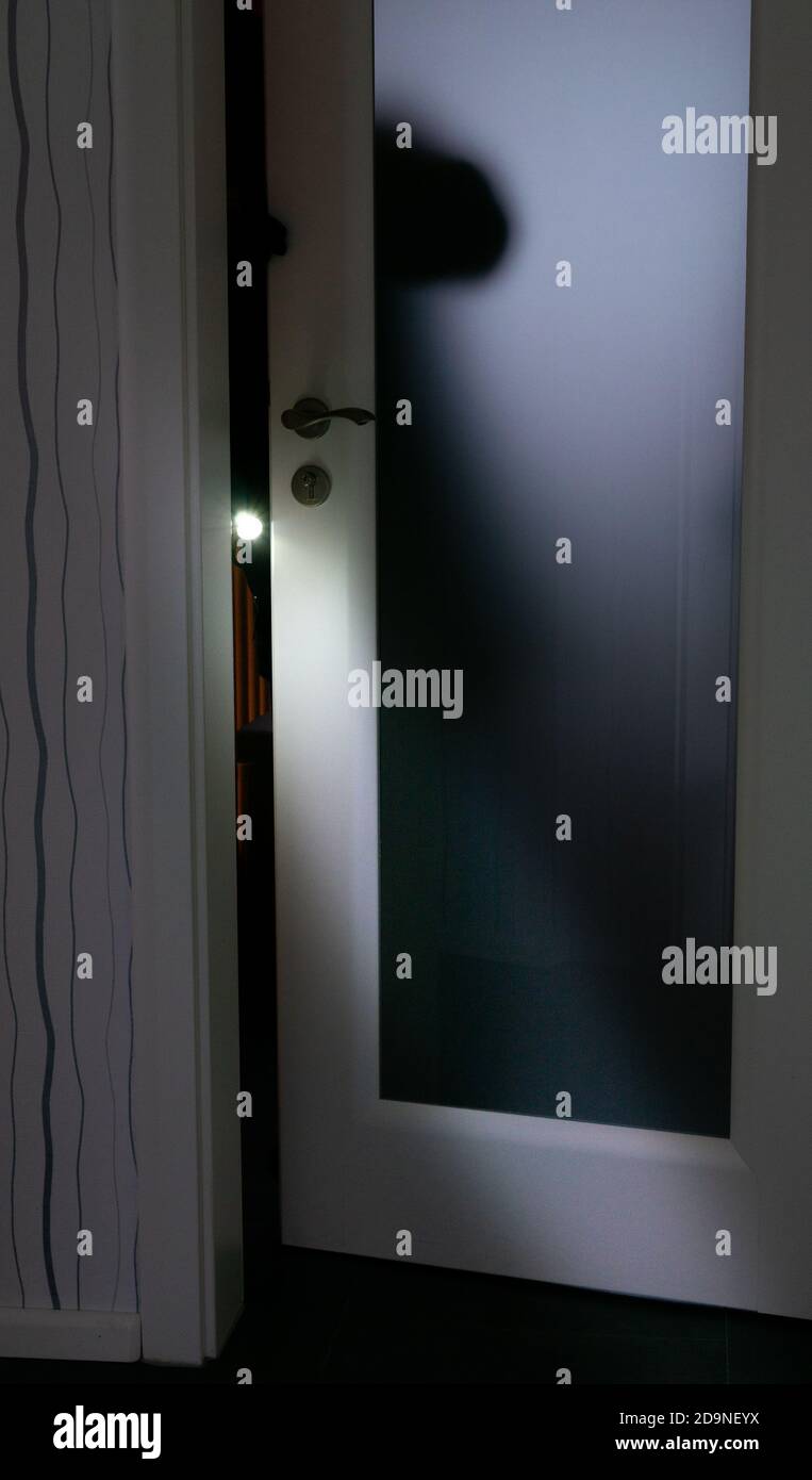 Burglar with a flashlight opening a door Stock Photo Alamy