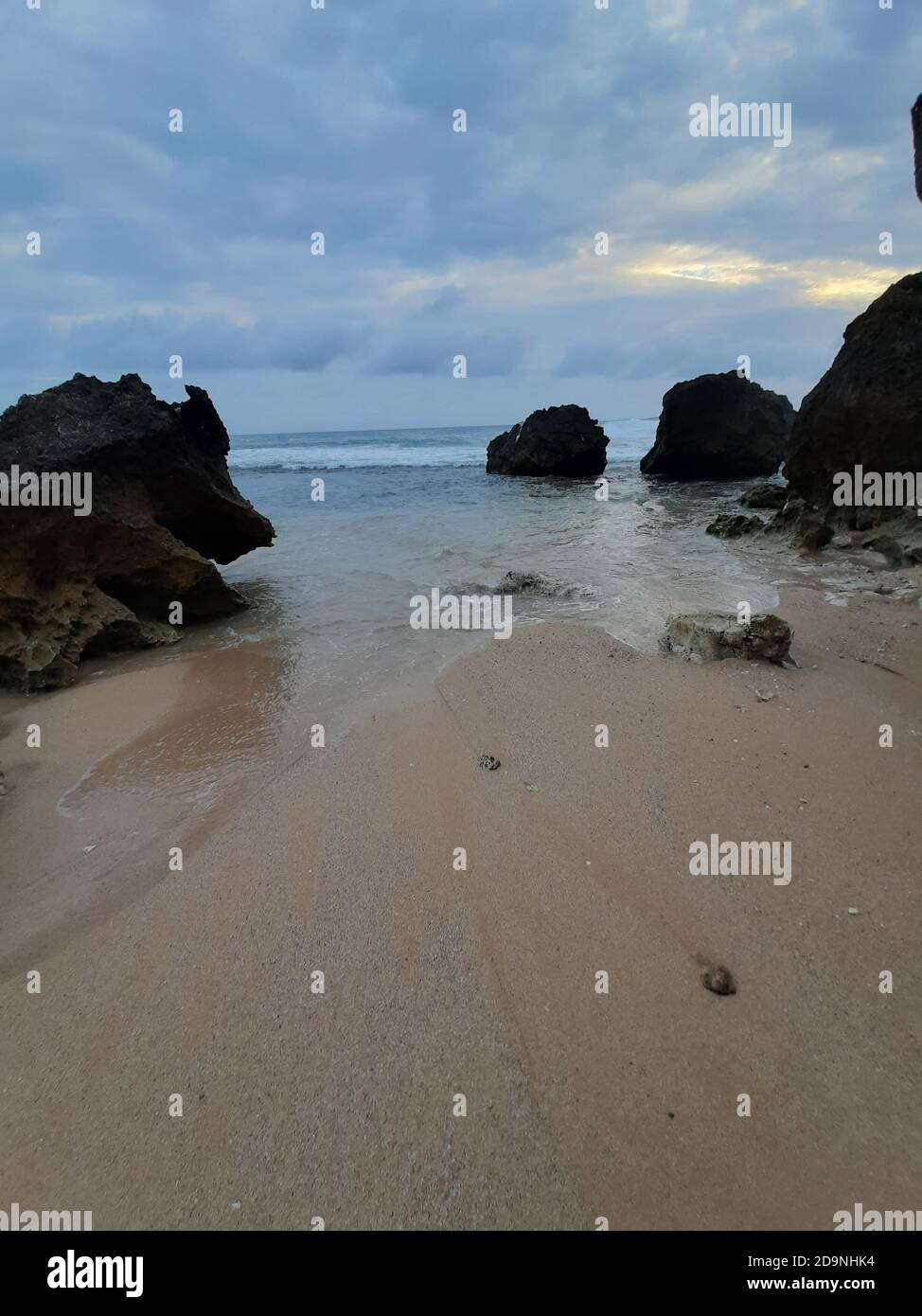 Single rocks on a sand beach against blue ocean and cloud sky at ...