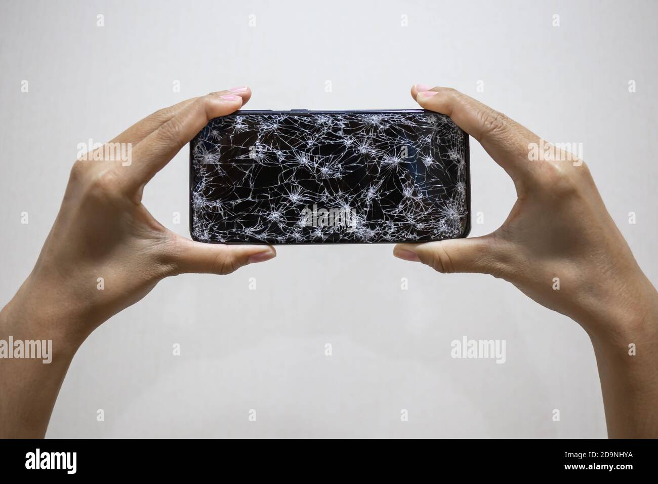 Woman hands holding smartphone with broken or cracked screen on white ...