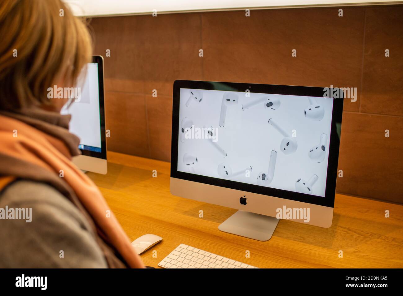 Paris, France - Nov 16, 2019: Side view of woman looking at the latest  Apple Computers iMac