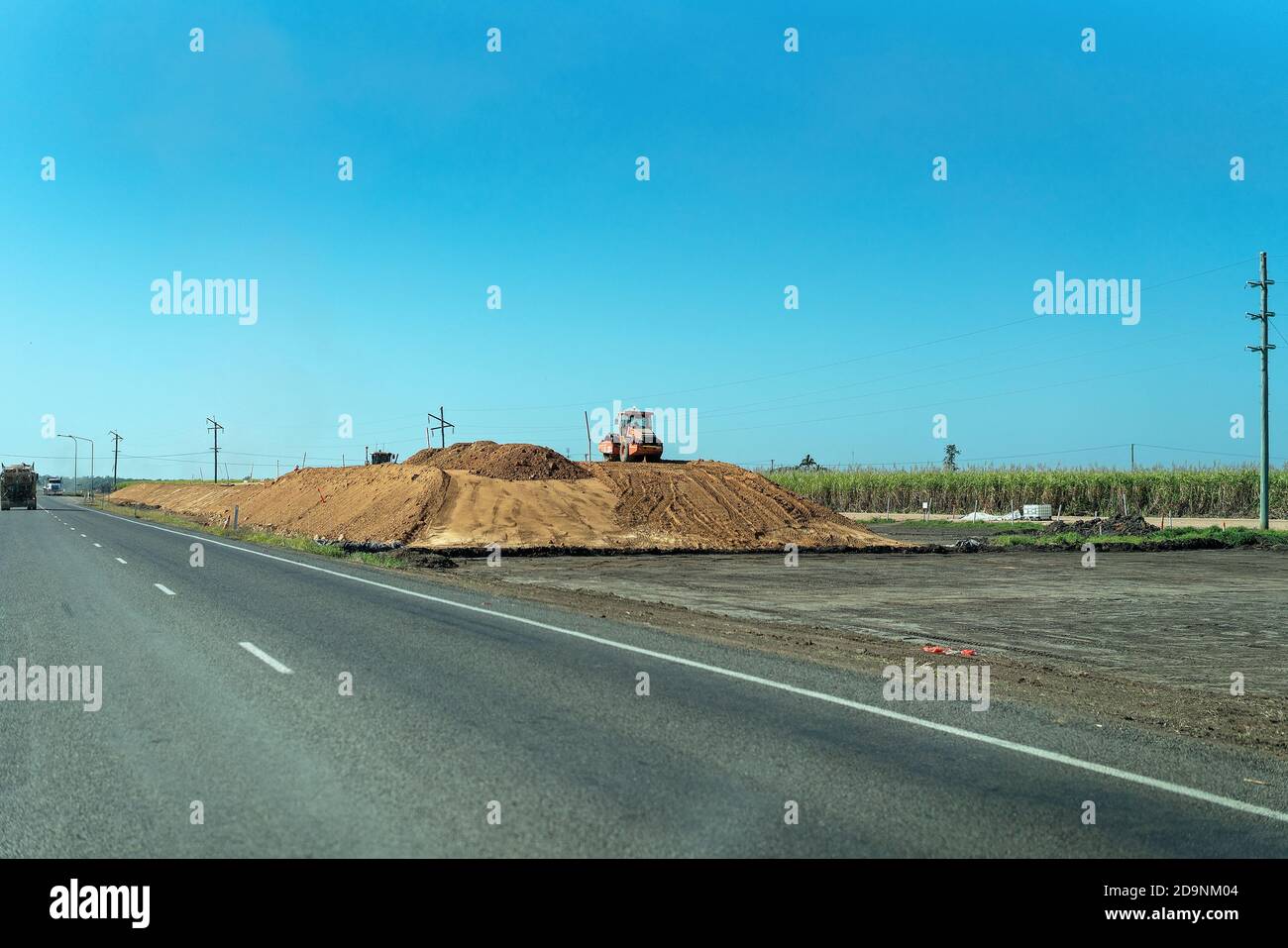 Bruce Highway, Queensland, Australia - August 19, 2019: Council Machinery compacting dirt for new road construction on busy highway Stock Photo