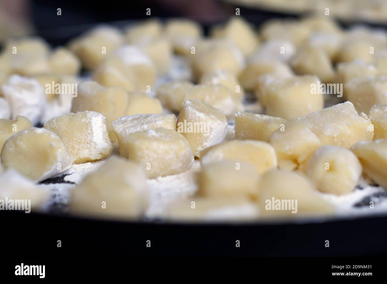 Many homemade gnocchi on a tray with the background blurred. Stock Photo