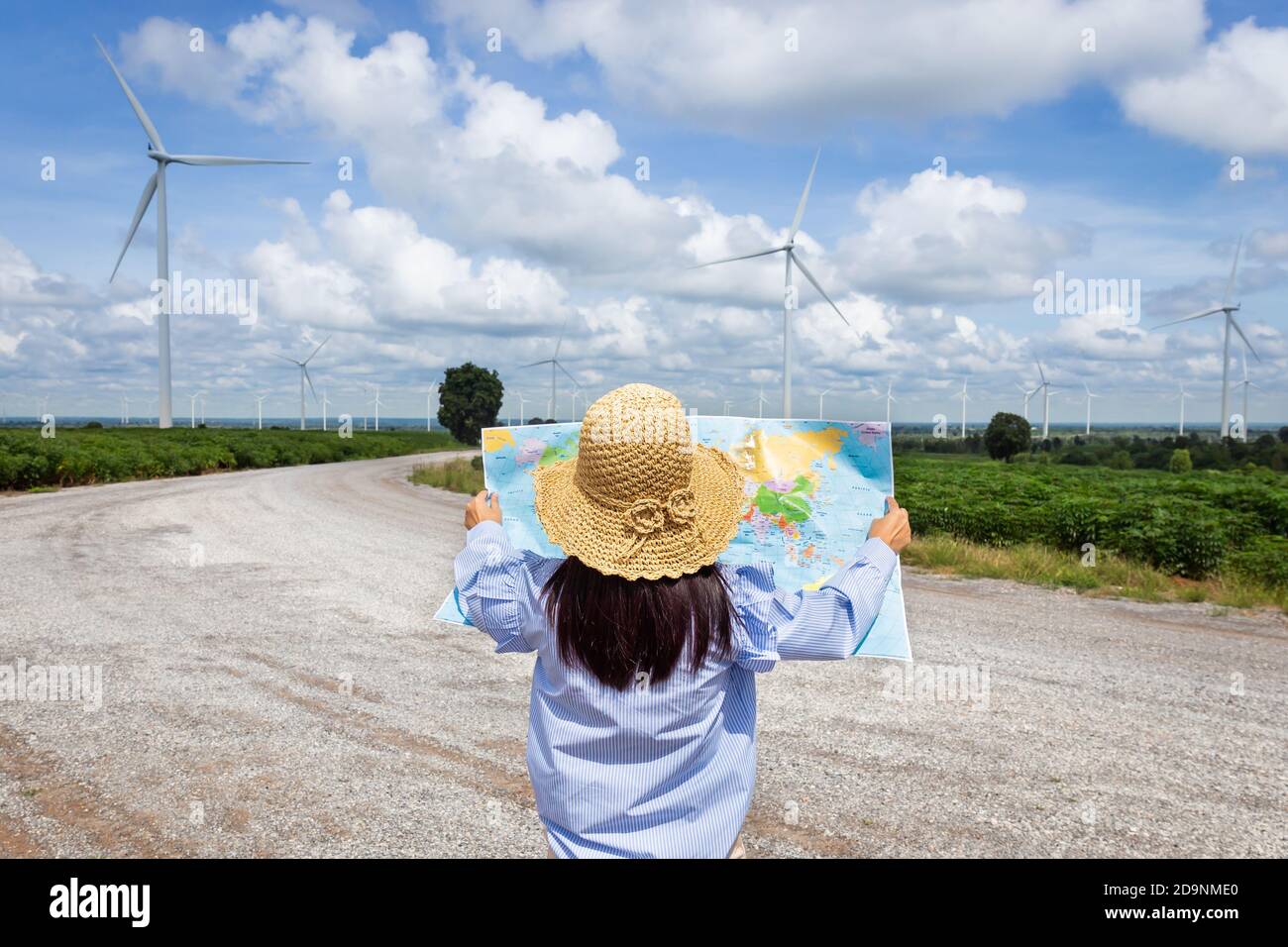 Woman stands looking at an outdoor map to travel to one of the holiday destinations. Stock Photo