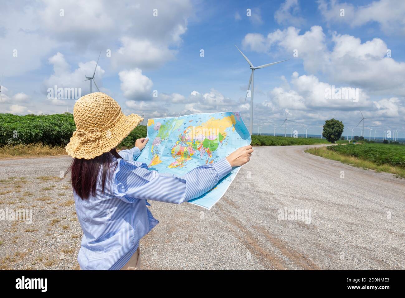 Woman stands looking at an outdoor map to travel to one of the holiday destinations. Stock Photo