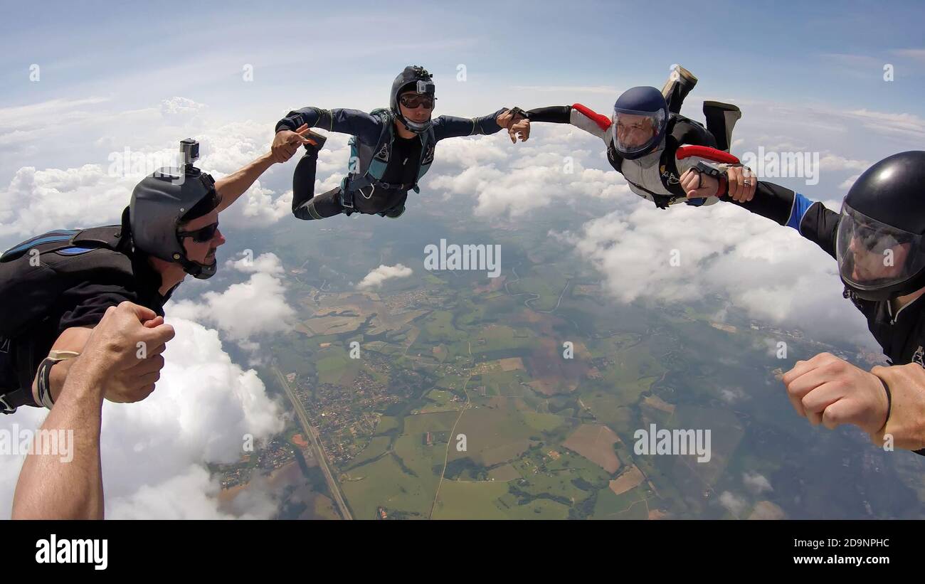 A group of friends holding hands teamwork in skydiving, soft focus on the clouds Stock Photo