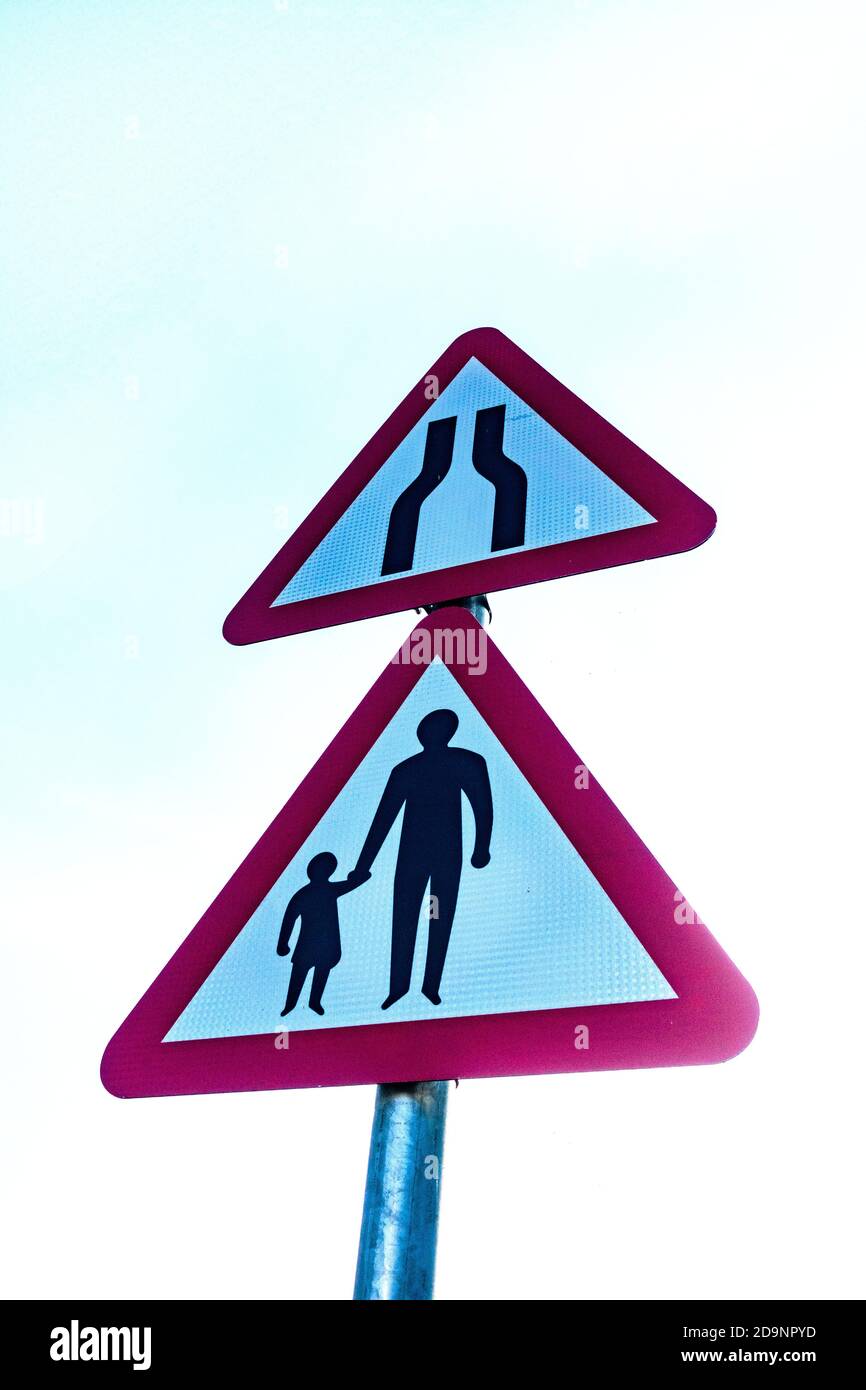 2 triangle warning signs, road narrows and family walking Stock Photo