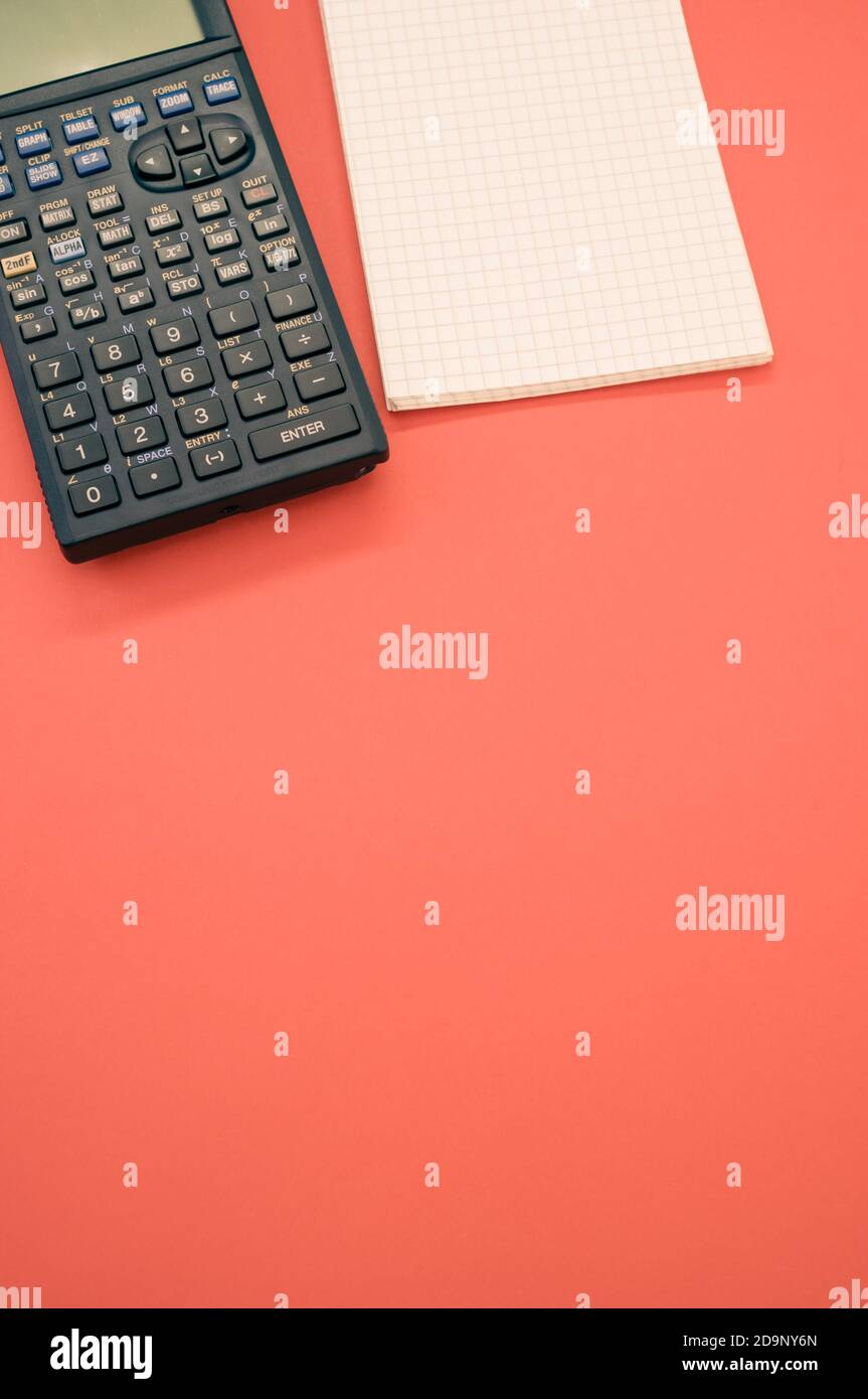 A top view closeup of a graphing calculator and a tiny notepad isolated