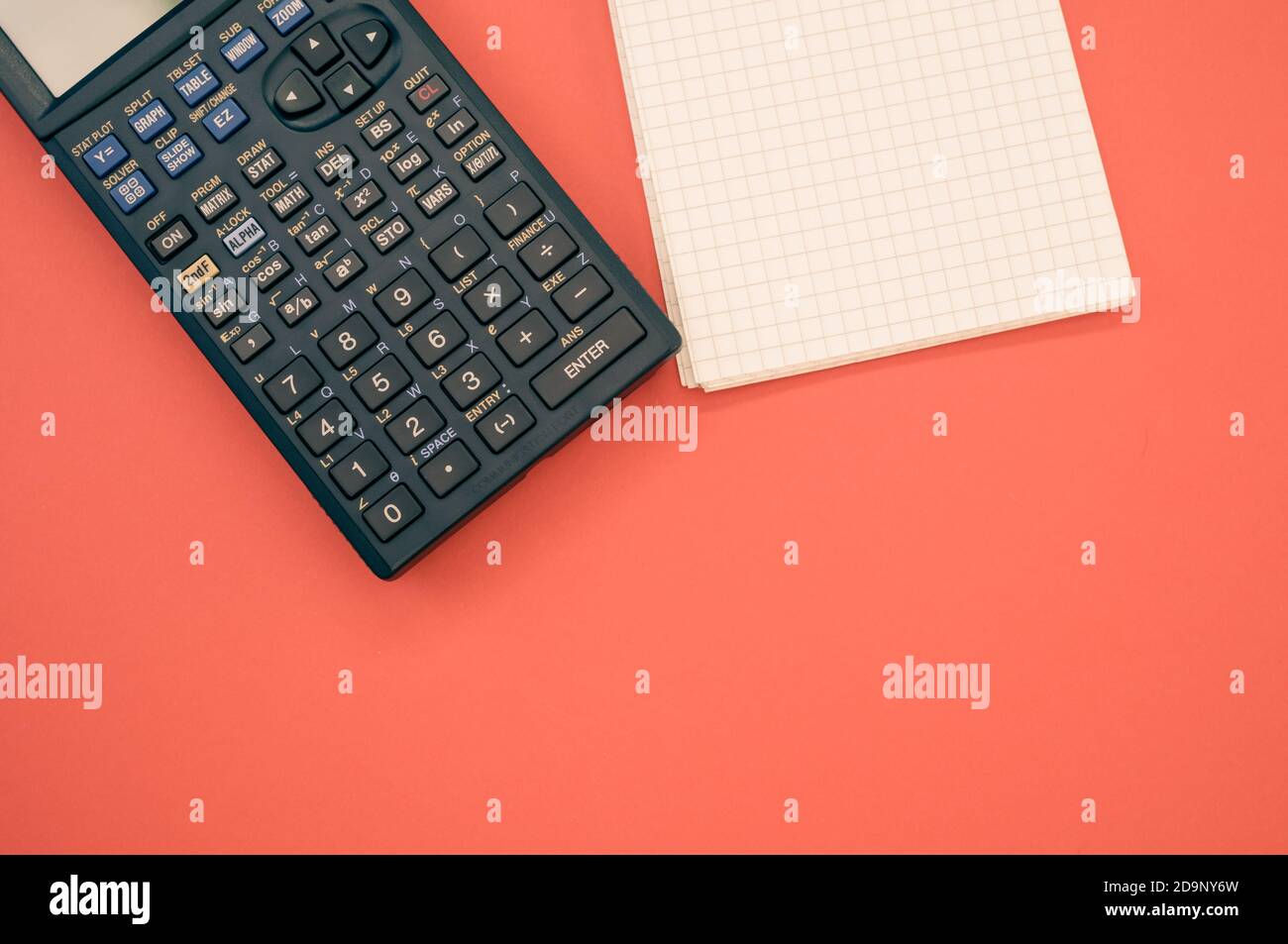 A top view closeup of a graphing calculator and a tiny notepad isolated ...