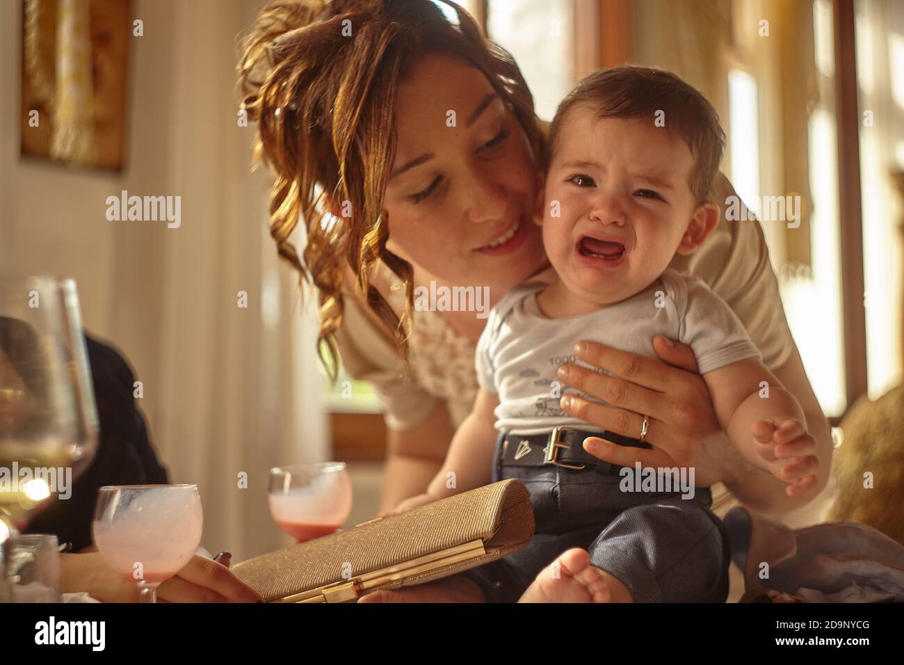 Young mom tries to reassure her crying baby. Stock Photo