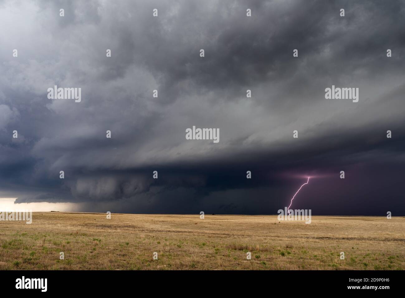 A supercell thunderstorm with stormy sky and cloud to ground lightning approaches Springfield, Colorado Stock Photo
