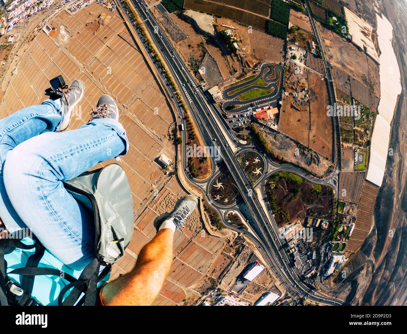 Air view of people couple doing paraglyde adrenaline experience - pilot and passenger paraglyiding over the city - outdoor excursion leisure activity Stock Photo