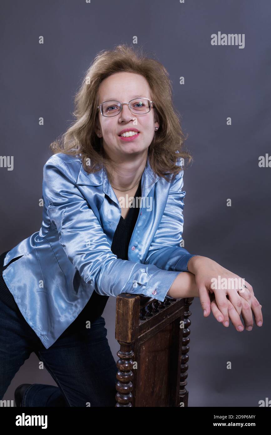 Cheerful 40 years old woman dressed in blue jeans and azure jacket
