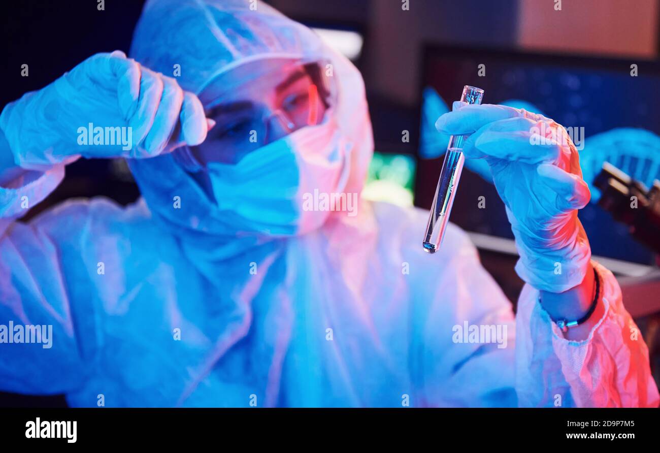 Nurse in mask and white uniform, holding tube with liquid and sitting ...