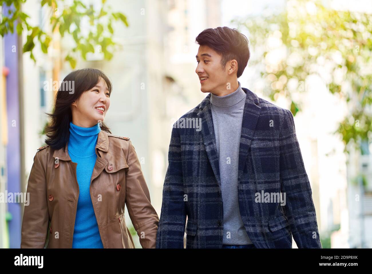 happy young asian couple walking chatting on street holding hands Stock Photo