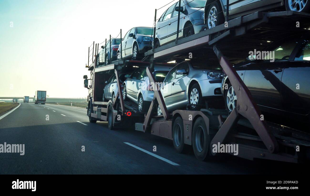 Car transporter trailer loaded with many cars on a highway, motion blur effect. Stock Photo