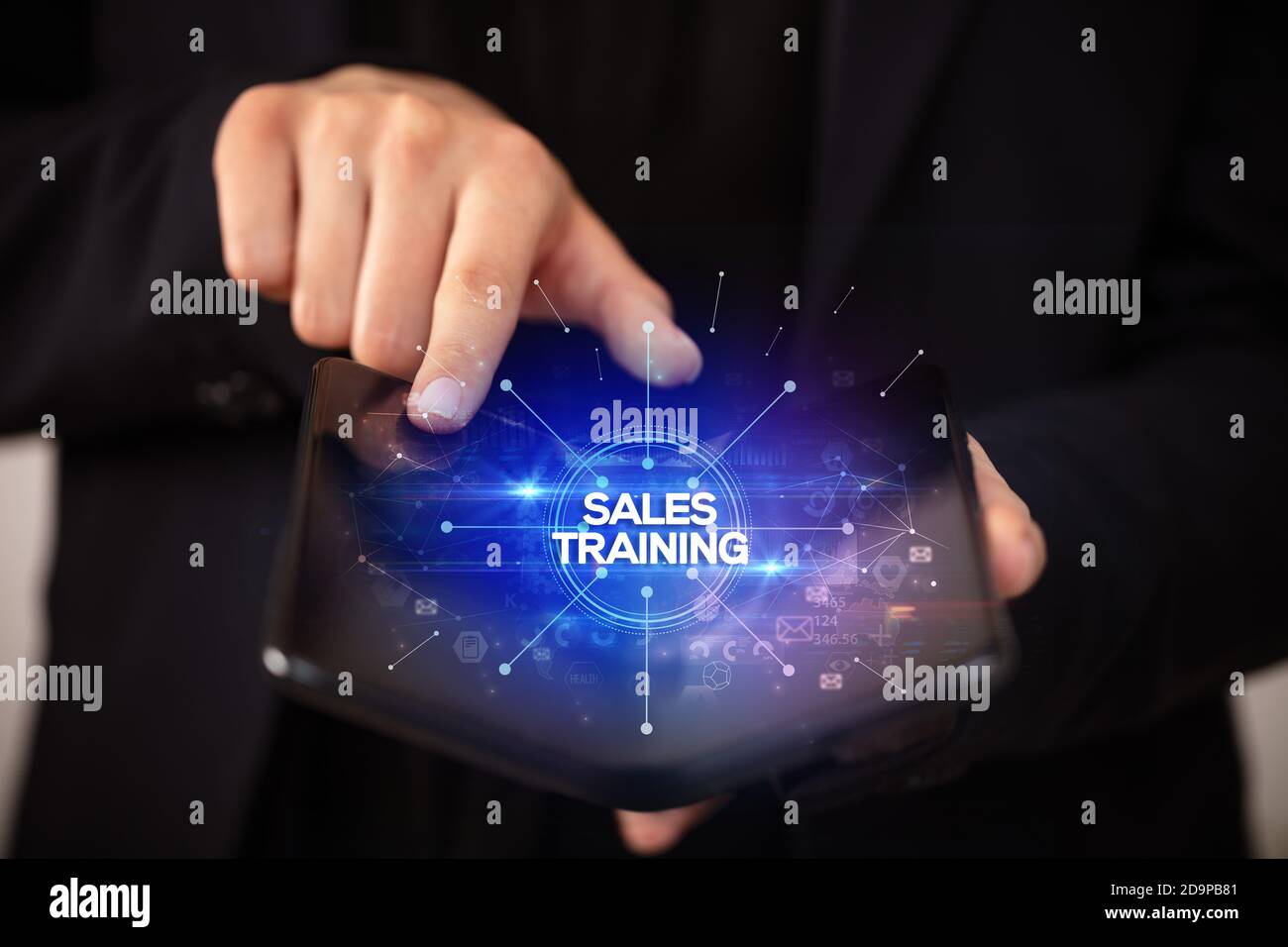 Businessman holding a foldable smartphone with SALES TRAINING inscription, new business concept Stock Photo