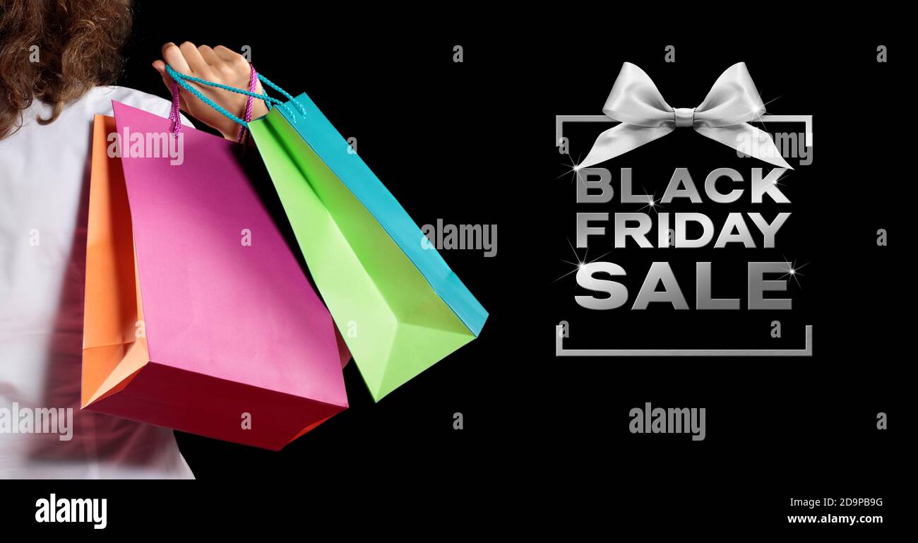 black friday sale, woman with shoppers bags and silver texts write on black background, useful for making an advertising billboard Stock Photo