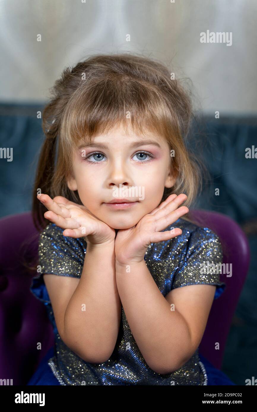 portrait of a beautiful little girl in a blue dress with makeup. professional makeup for children Stock Photo