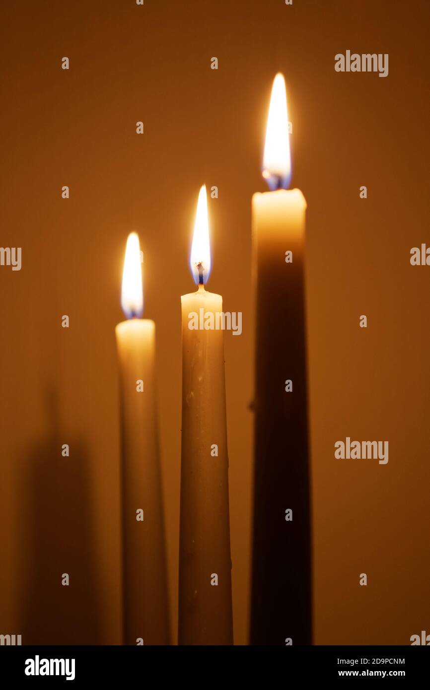 Three candles in the dark room against a wall. Shallow DOF. Focus on