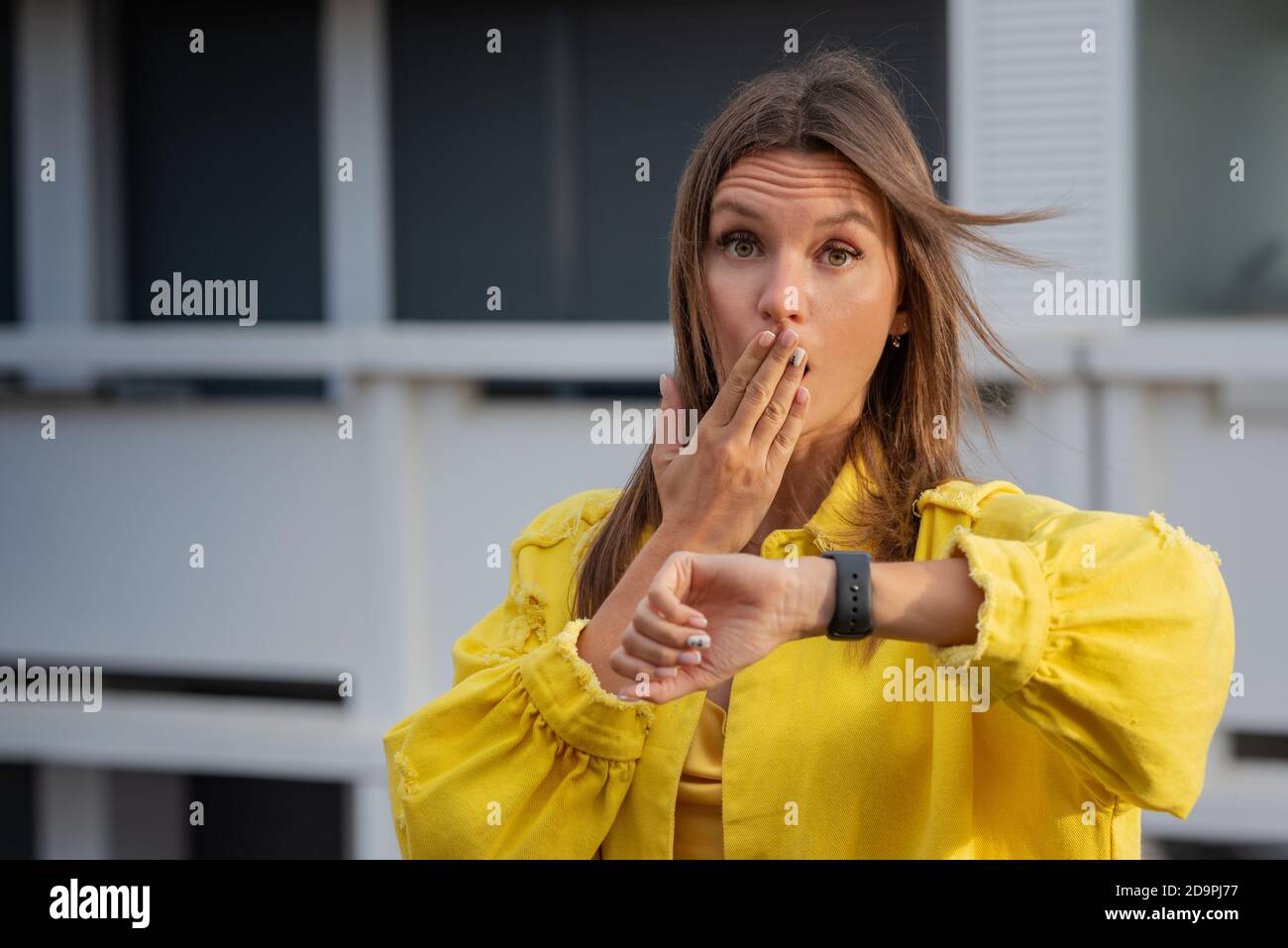 Young woman checking time on a smartwatch and feels stressed because of being late. Woman forgot about a meeting. Stock Photo