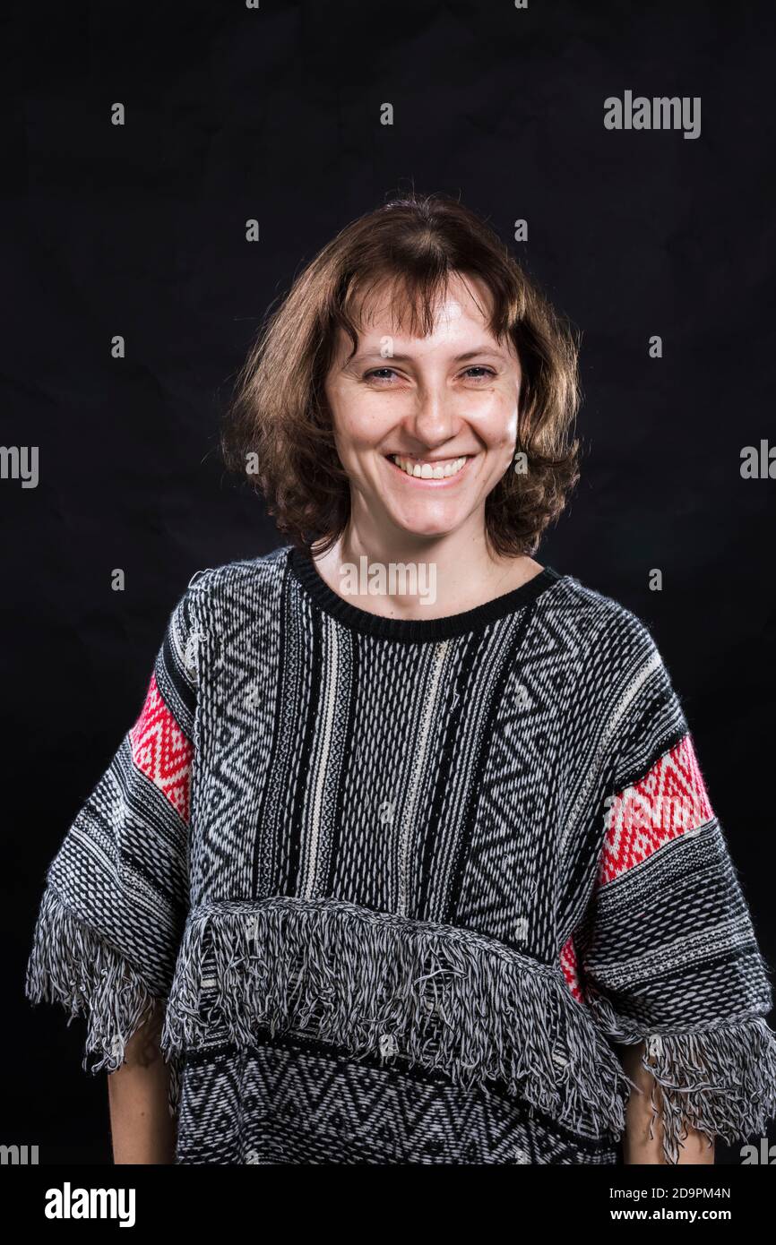 Cheerful 40 years old woman dressed in jeans and poncho studio portrait