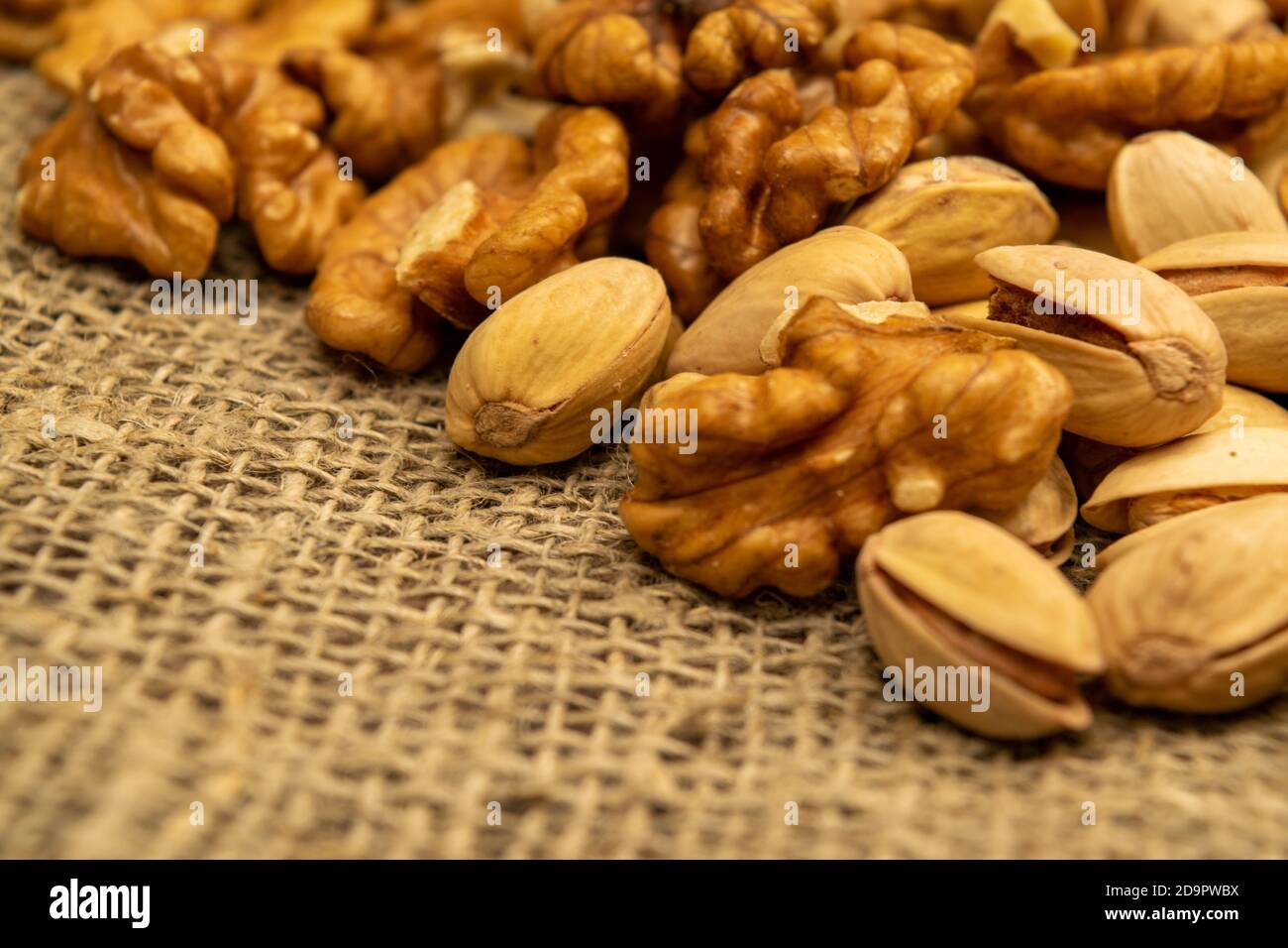 Pistachios and walnuts lie on the sacking. Close up Stock Photo