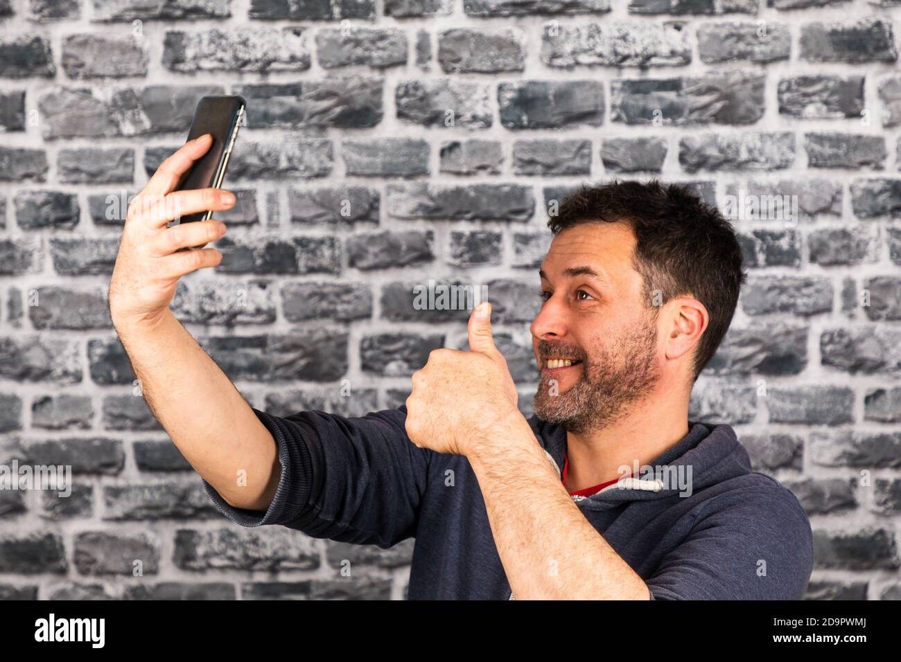 Caucasian man with a beard taking a selfie with his smartphone, while ...