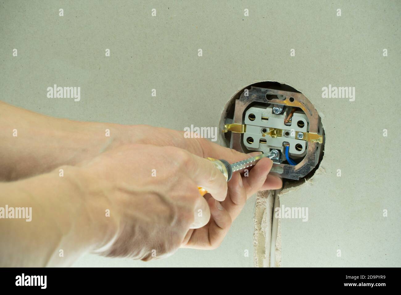 Installation wire into a plug. A man installs an electrical outlet in