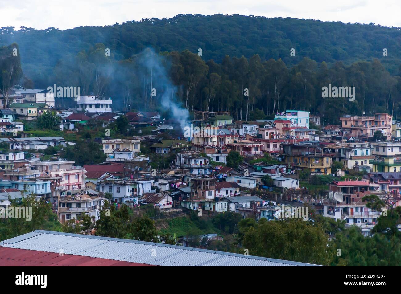 Smoke rises from an outdoor fire in a residential area in Shillong, Meghalaya, India. Poor urban planning makes the locality look like a favela. Stock Photo