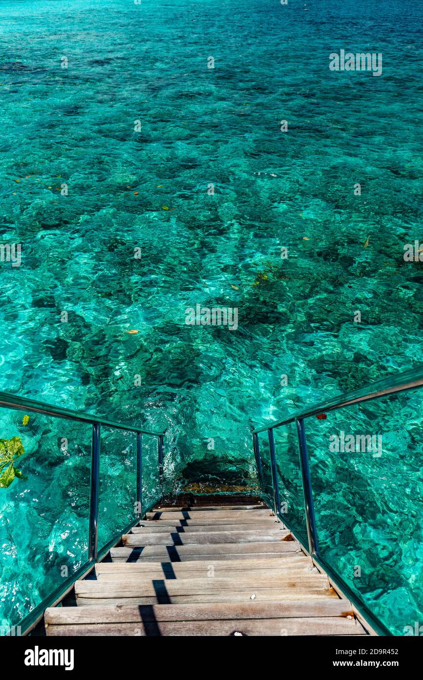 Jetty over swimming atoll and a tropical resort island in Maldives ...