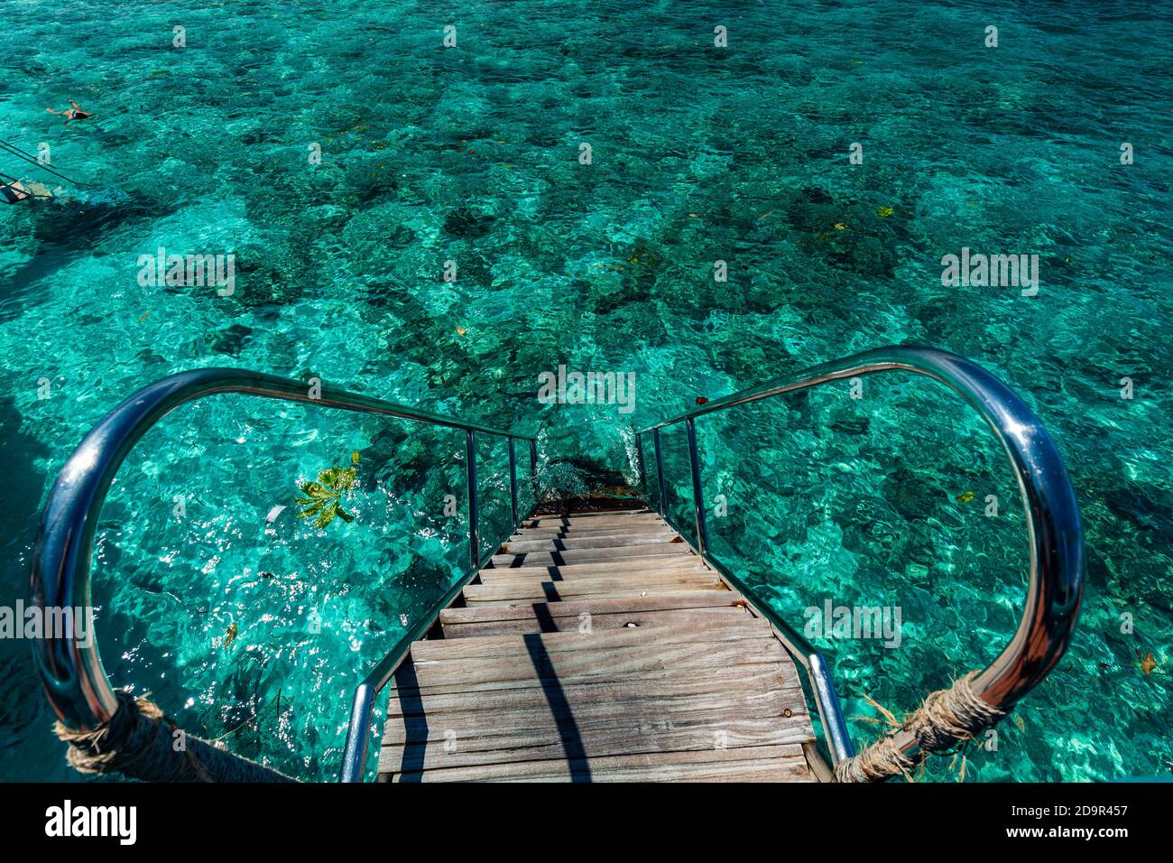 Jetty over swimming atoll and a tropical resort island in Maldives ...