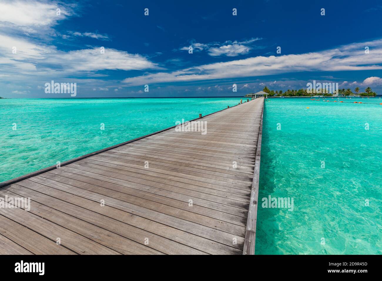Jetty over swimming atoll and a tropical resort island in Maldives ...