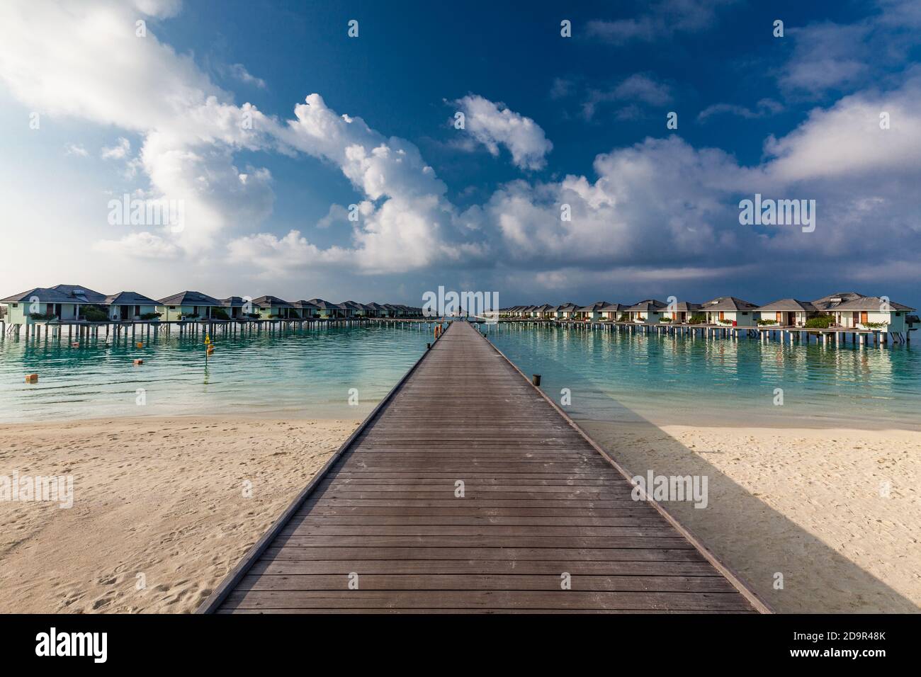Jetty over swimming atoll and a tropical resort island in Maldives ...