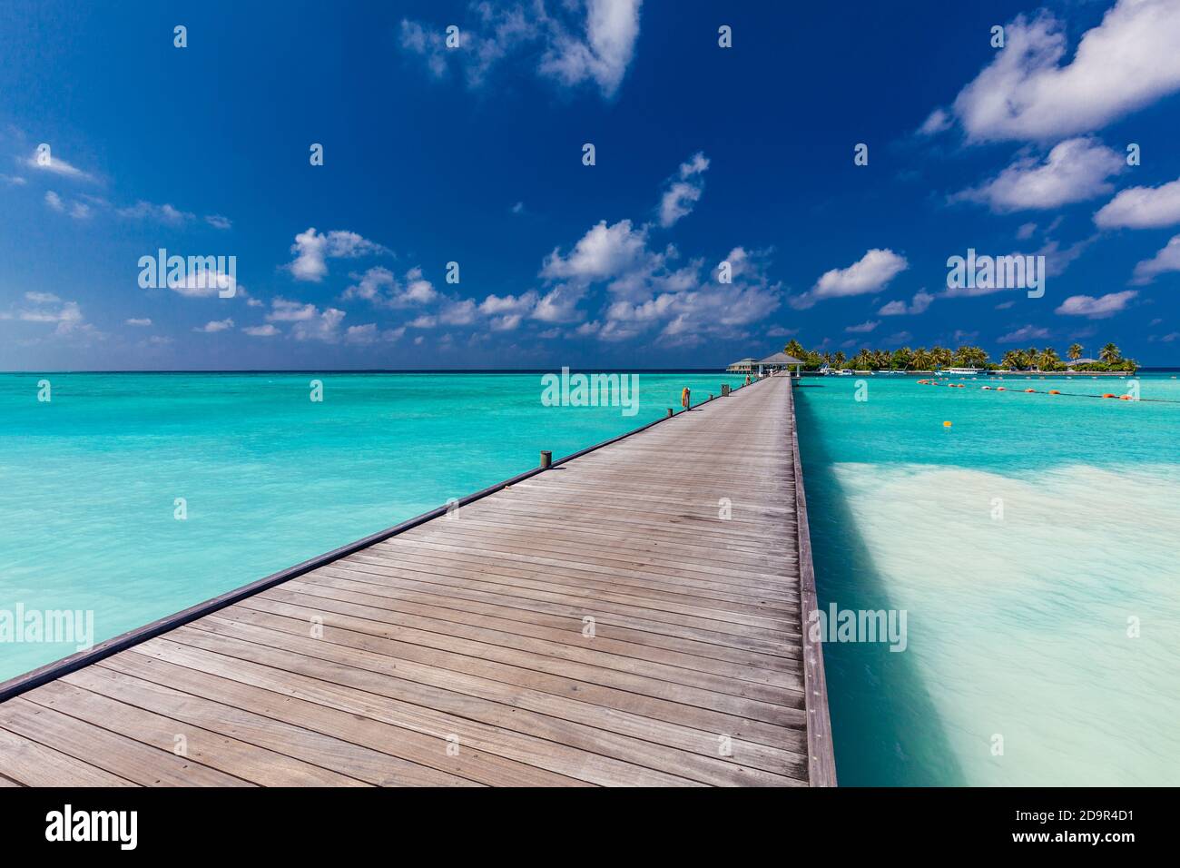 Jetty over swimming atoll and a tropical resort island in Maldives ...