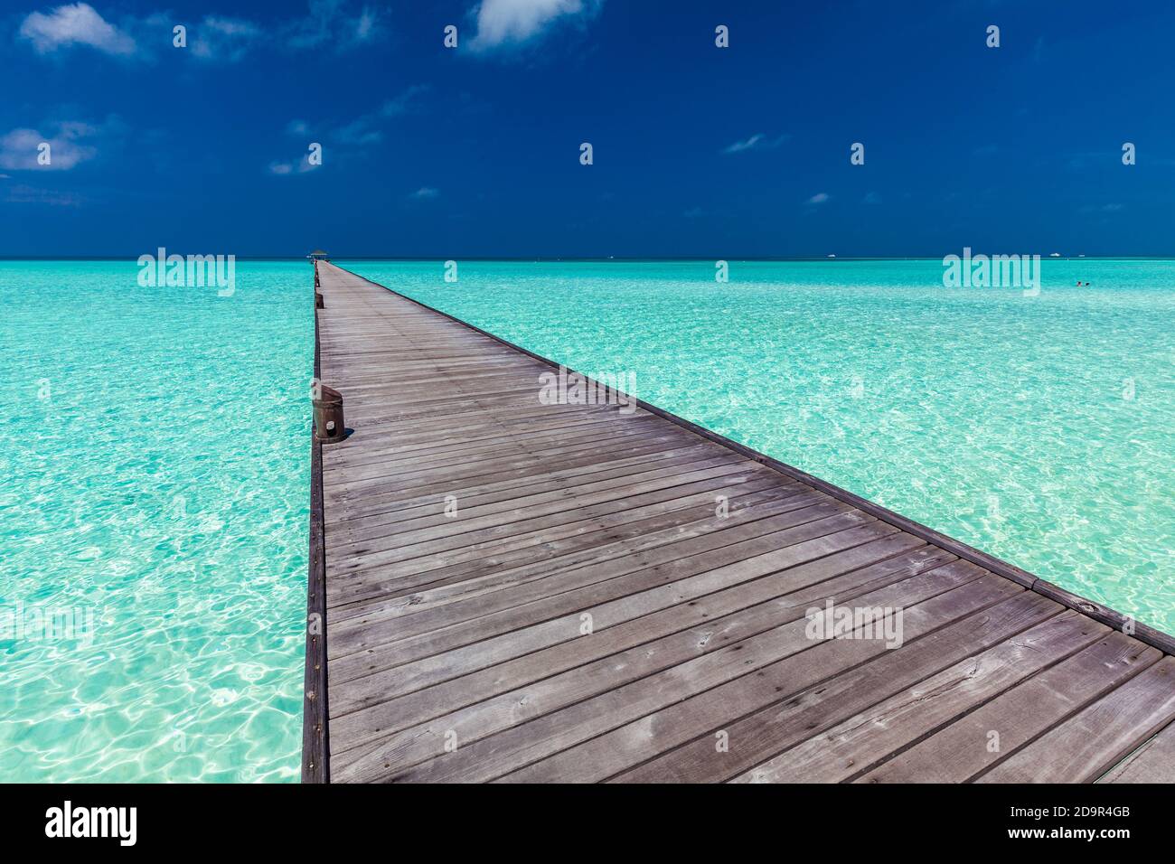 Jetty over swimming atoll and a tropical resort island in Maldives ...