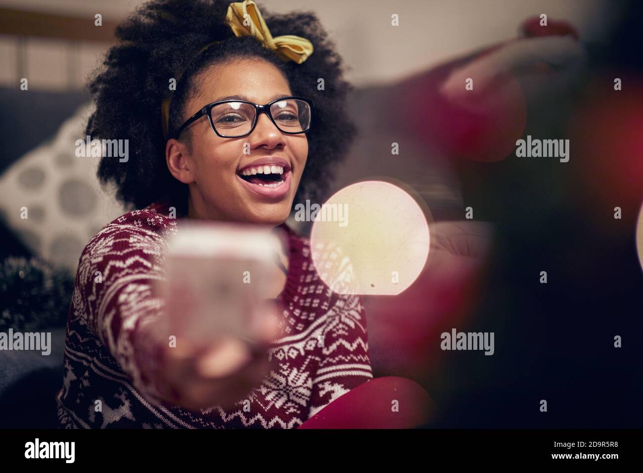 Cheerful afro american teenage girl reciving xmas present; Happy family moments concept Stock Photo