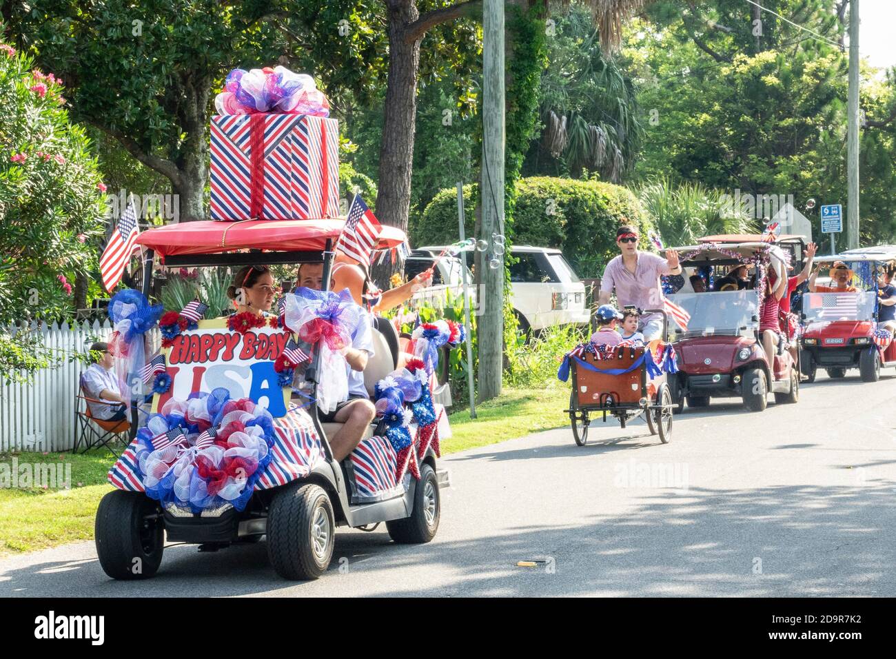 Decorated golf cart floats and bicycles ride down the road during the annual Independence Day parade July 4, 2019 in Sullivan's Island, South Carolina. The tiny affluent Sea Island beach community across from Charleston holds an outsized golf cart parade featuring more than 75 decorated carts. Stock Photo
