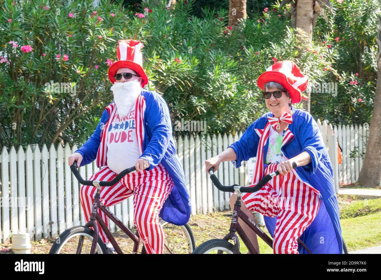 Dressed as Uncle Sam in patriotic colors bicyclists ride down the road during the annual Independence Day parade July 4, 2019 in Sullivan's Island, South Carolina. The tiny affluent Sea Island beach community across from Charleston holds an outsized golf cart parade featuring more than 75 decorated carts. Stock Photo