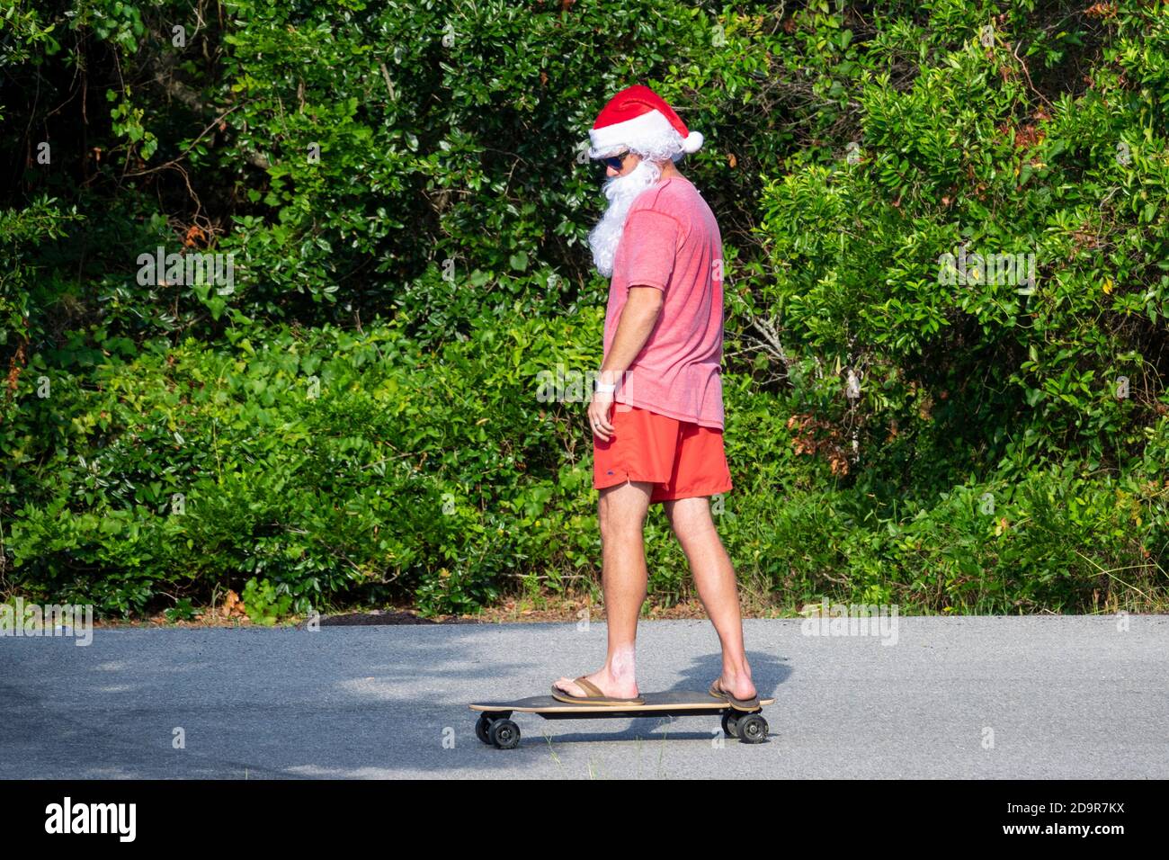 Dressed as beach Santa a man rides a skateboard in the annual Independence Day parade July 4, 2019 in Sullivan's Island, South Carolina. The tiny affluent Sea Island beach community across from Charleston holds an outsized golf cart parade featuring more than 75 decorated carts. Stock Photo