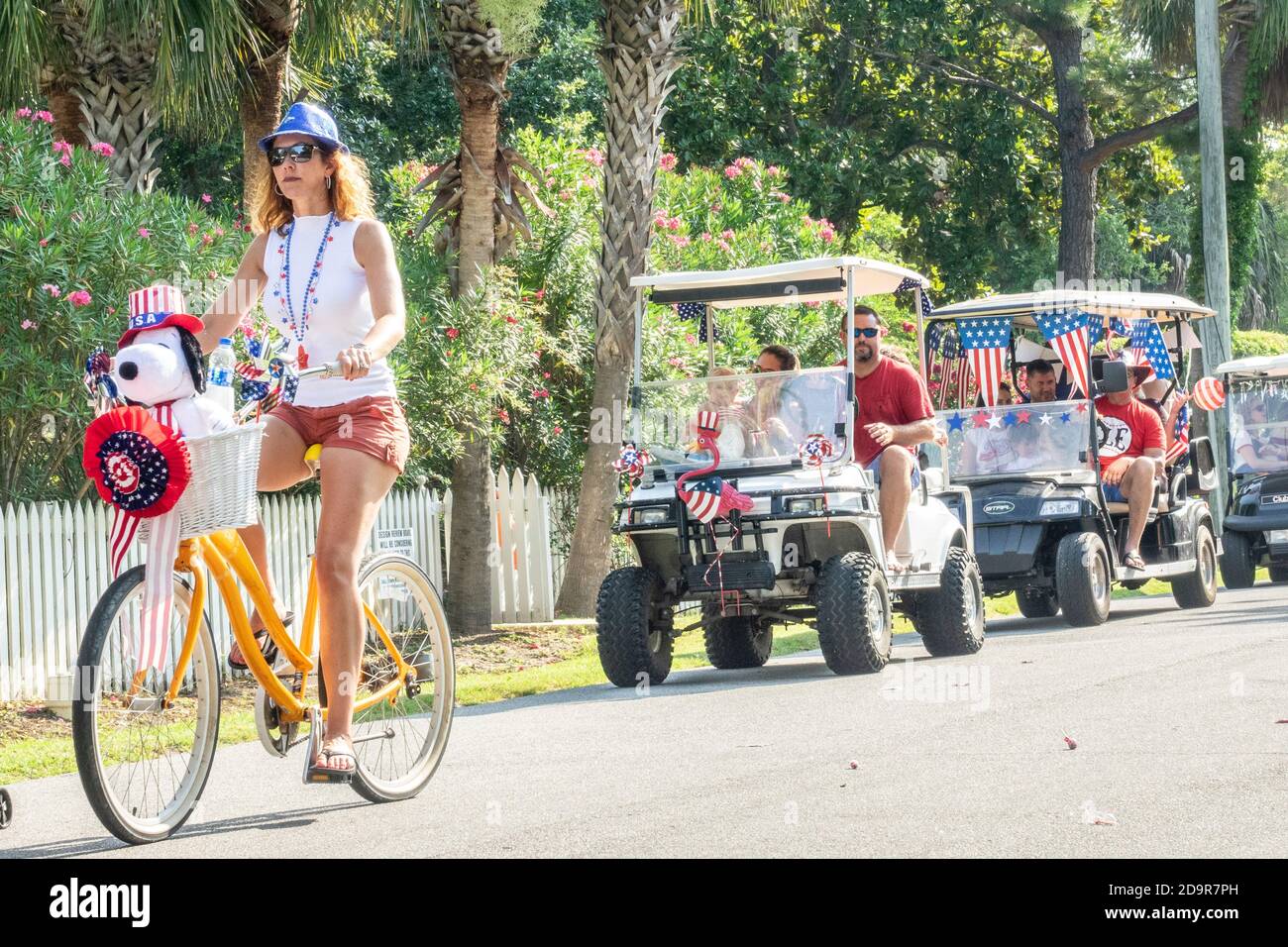 Dressed in costumes bicyclists and decorated golf carts ride down the road during the annual Independence Day parade July 4, 2019 in Sullivan's Island, South Carolina. The tiny affluent Sea Island beach community across from Charleston holds an outsized golf cart parade featuring more than 75 decorated carts. Stock Photo