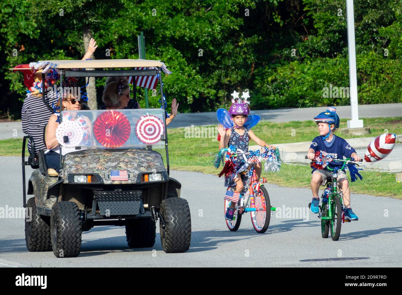 Decorated golf carts and costumed bicyclists ride down the road during the annual Independence Day parade July 4, 2019 in Sullivan's Island, South Carolina. The tiny affluent Sea Island beach community across from Charleston holds an outsized golf cart parade featuring more than 75 decorated carts. Stock Photo