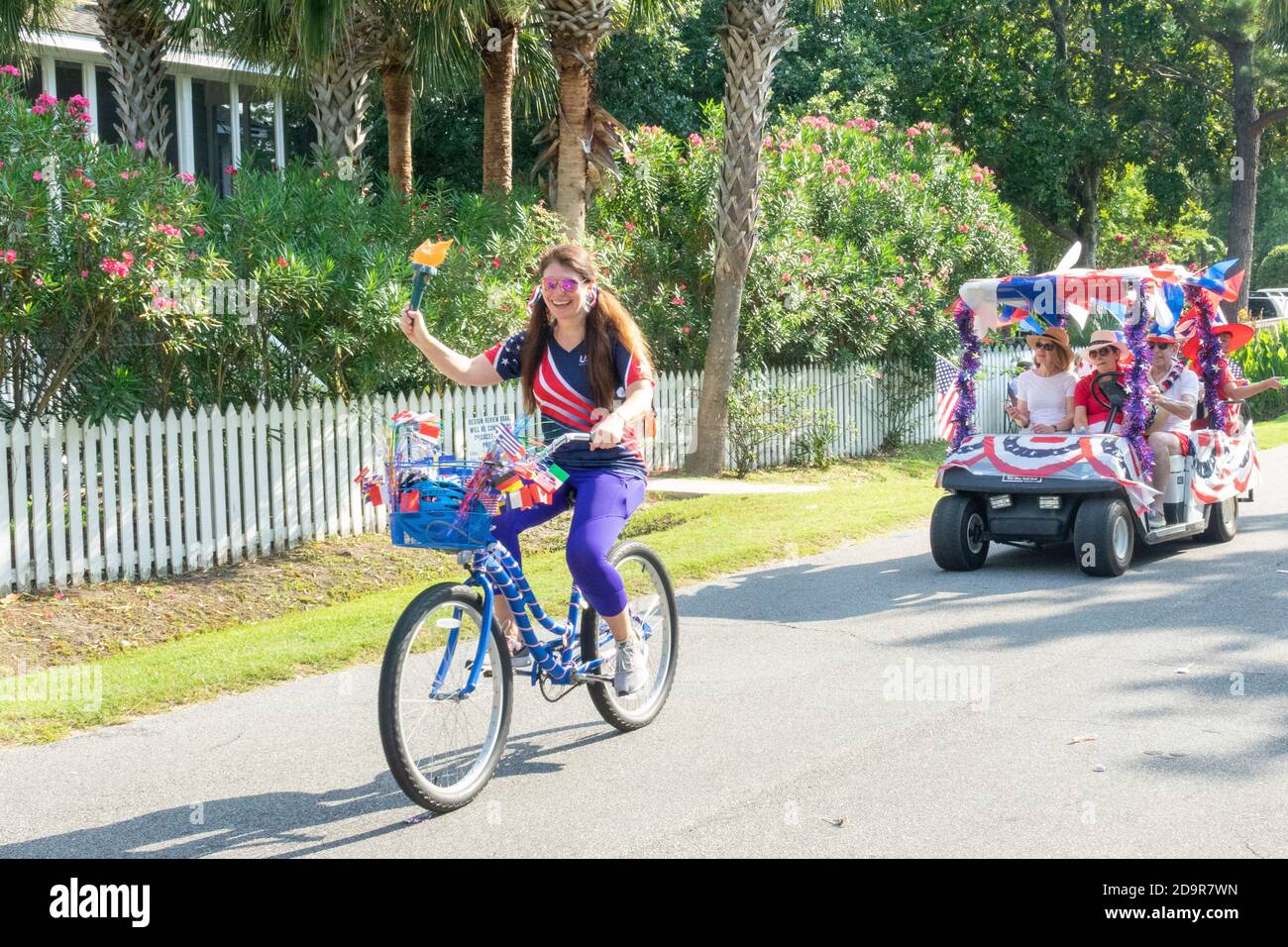 Decorated golf carts and costumed bicyclists ride down the road during the annual Independence Day parade July 4, 2019 in Sullivan's Island, South Carolina. The tiny affluent Sea Island beach community across from Charleston holds an outsized golf cart parade featuring more than 75 decorated carts. Stock Photo
