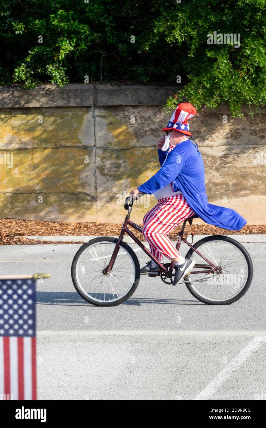 A man dressed in an Uncle Sam costume rides his bicycle in the annual Independence Day golf cart and bicycle parade July 4, 2019 in Sullivan's Island, South Carolina. The tiny affluent Sea Island beach community across from Charleston holds an outsized golf cart parade featuring more than 75 decorated carts. Stock Photo