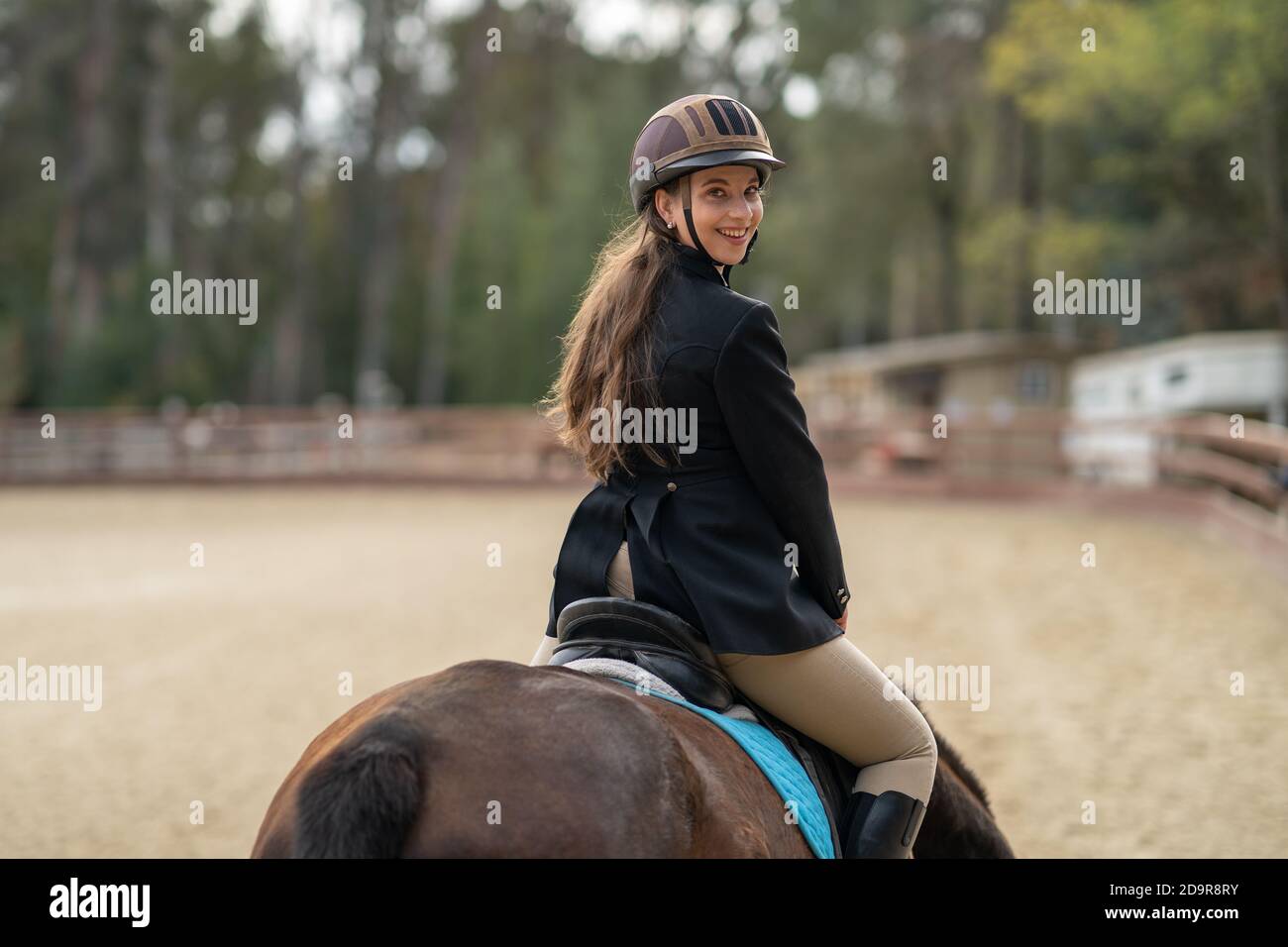 woman riding horse, english saddle, in arena surrounded by oak trees Stock Photo