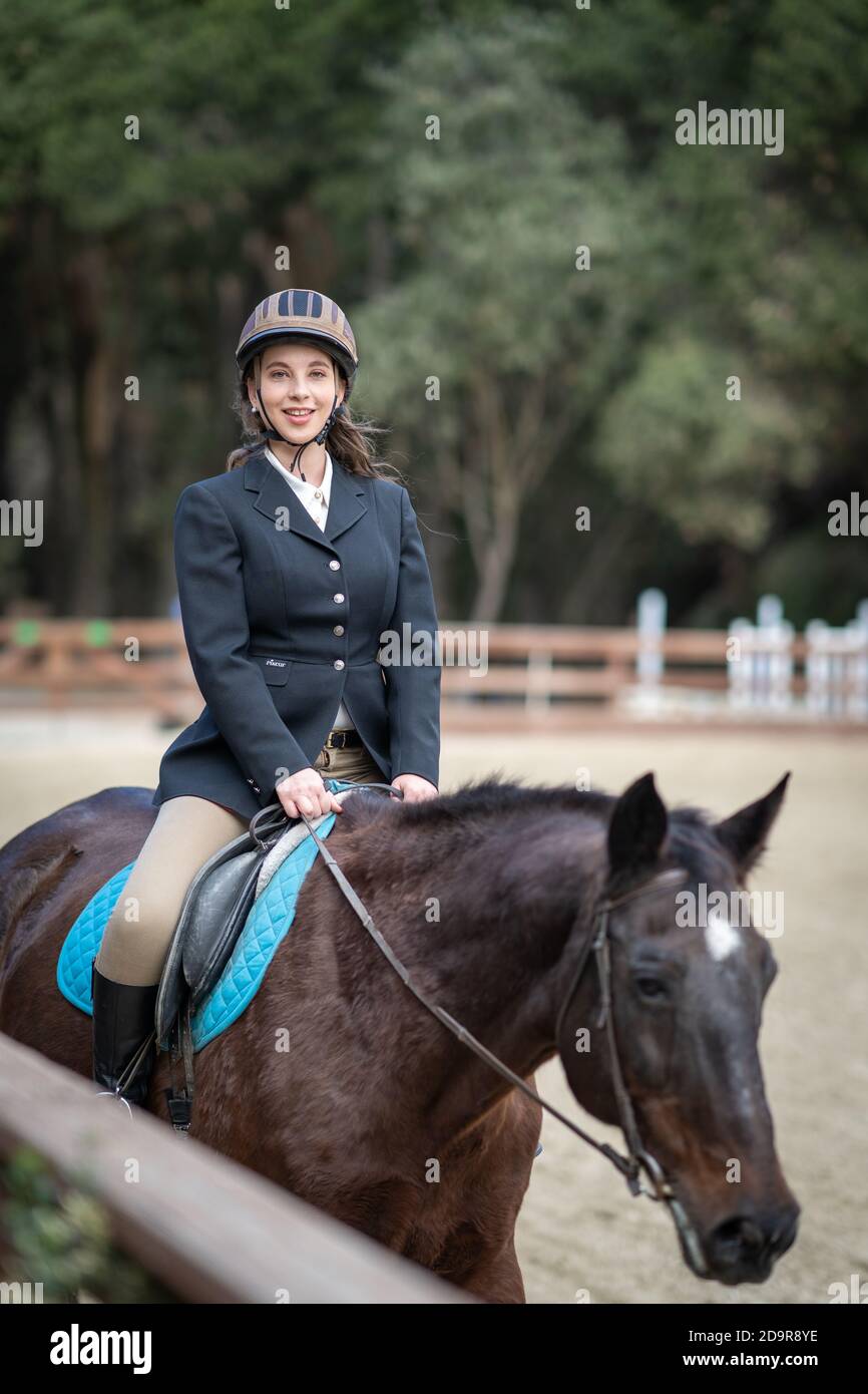 woman riding horse, english saddle, in arena surrounded by oak trees Stock Photo