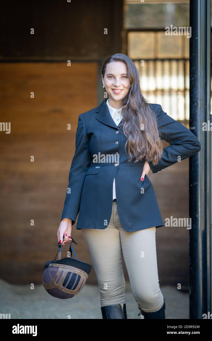 equestrian woman dressed in english riding standing outside stable door ...