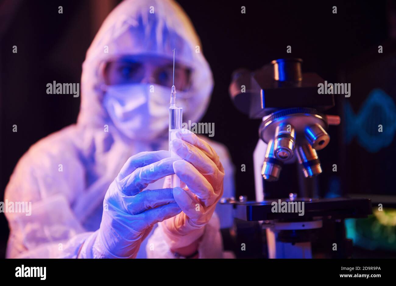 Nurse in mask and white uniform, holding syringe and sitting in neon ...